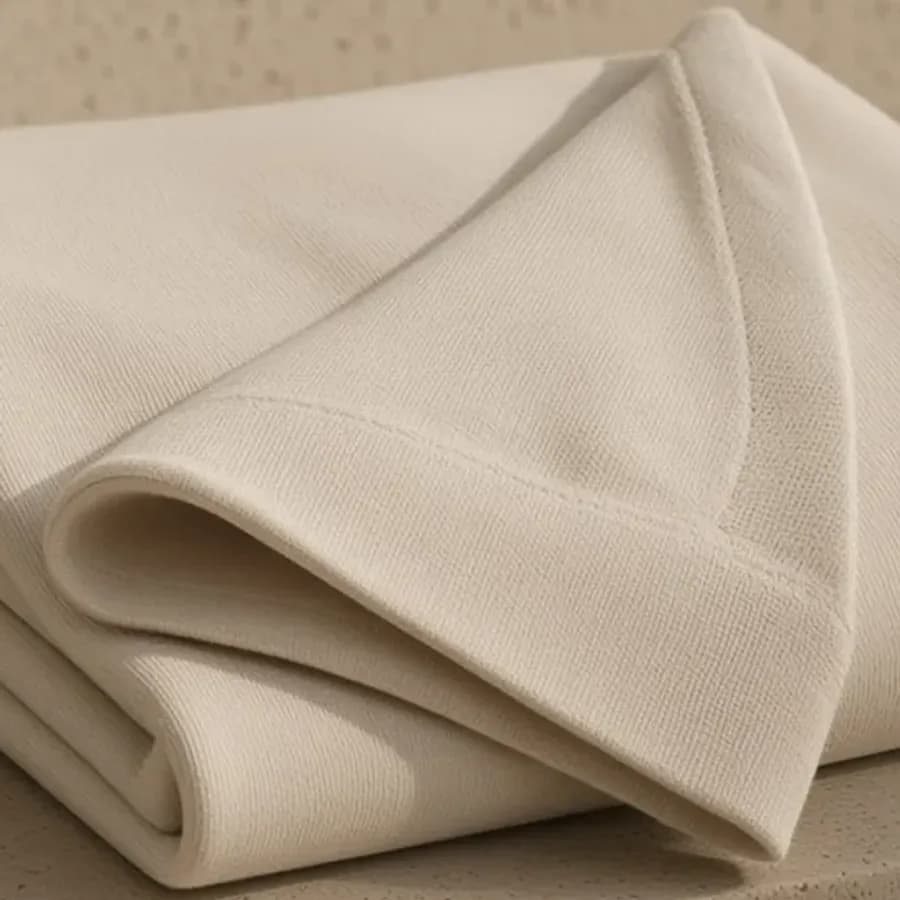 An ivory cotton rib, turned back on a folded sweatshirt.